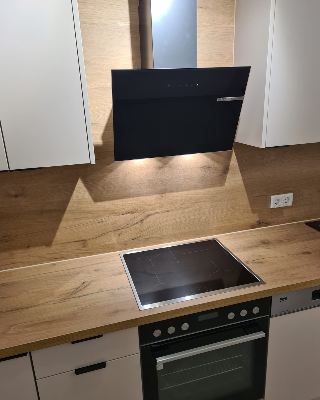 Renovierte Küche mit Holzarbeitsplatte, Induktionskochfeld und neuer Dunstabzugshaube.