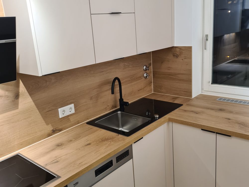 Renovierte Küche mit weißer Einbauküche und Holzarbeitsplatte.